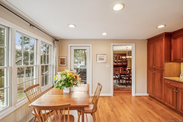 dining area with light wood-type flooring and an inviting chandelier