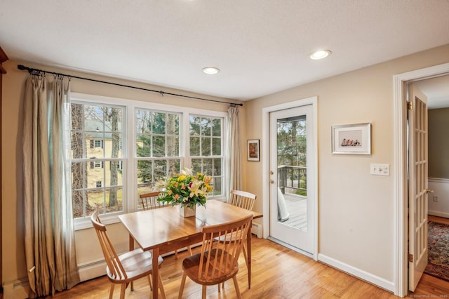 dining room with a baseboard heating unit and light hardwood / wood-style flooring