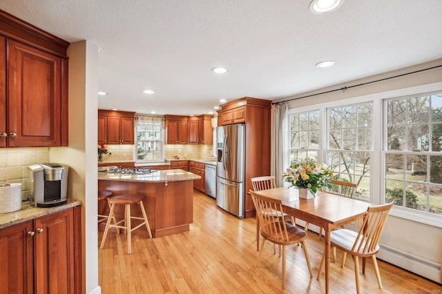 kitchen with a kitchen bar, appliances with stainless steel finishes, decorative backsplash, and light stone counters