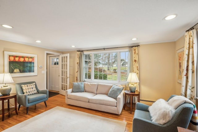 living room featuring light wood-type flooring, ornamental molding, and a baseboard radiator