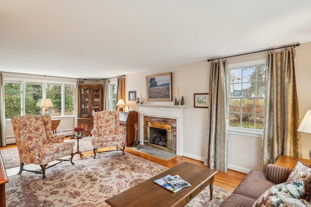 living room with light hardwood / wood-style floors, a brick fireplace, a wealth of natural light, and a baseboard heating unit