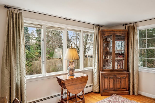 sitting room with a healthy amount of sunlight, a baseboard heating unit, and light wood-type flooring