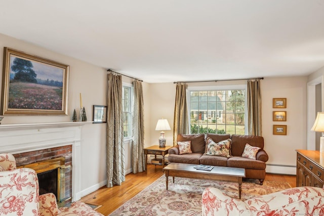 living room featuring a brick fireplace, light hardwood / wood-style floors, and a baseboard heating unit