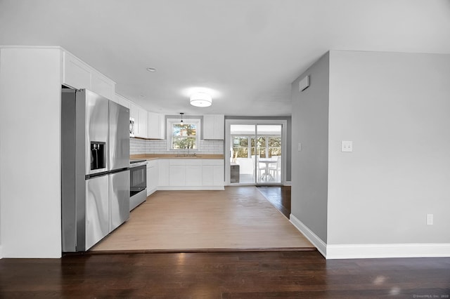 kitchen with decorative backsplash, stainless steel fridge, wood-type flooring, range, and white cabinetry