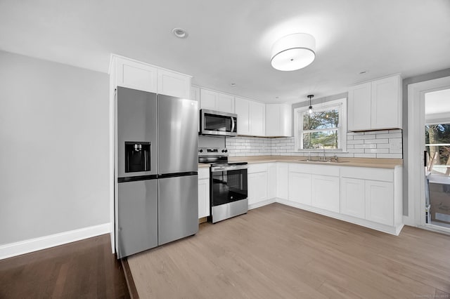 kitchen with decorative light fixtures, sink, white cabinetry, and stainless steel appliances