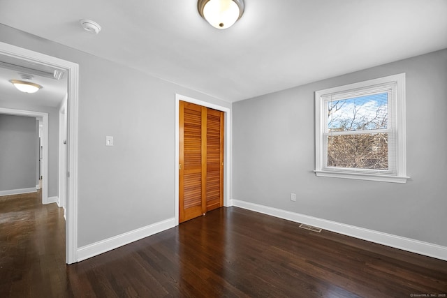 unfurnished bedroom with dark hardwood / wood-style flooring and a closet