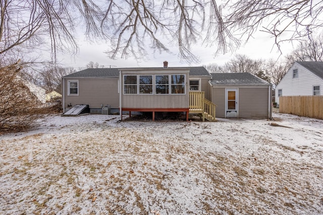 snow covered rear of property featuring a sunroom