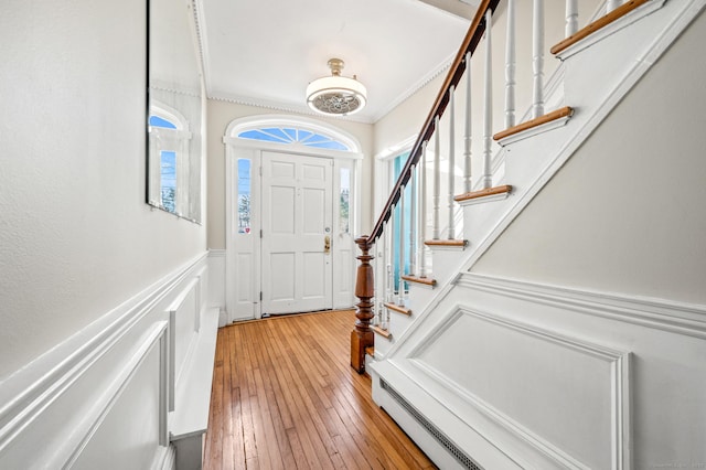 entrance foyer featuring ornamental molding, light wood-type flooring, and a baseboard heating unit