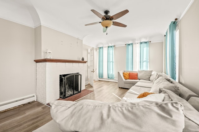 living room with ceiling fan, light hardwood / wood-style flooring, a baseboard heating unit, crown molding, and a fireplace