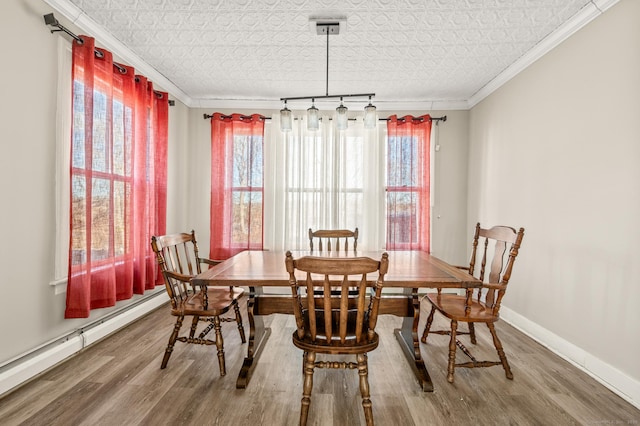 dining room featuring baseboard heating, crown molding, and wood-type flooring