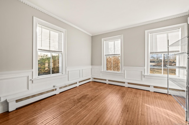 unfurnished room featuring a healthy amount of sunlight, hardwood / wood-style flooring, and crown molding