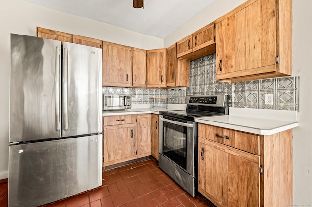 kitchen with backsplash, ceiling fan, dark tile patterned floors, and stainless steel appliances