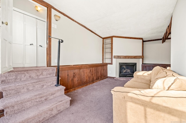 living room featuring lofted ceiling, crown molding, wooden walls, a textured ceiling, and carpet floors