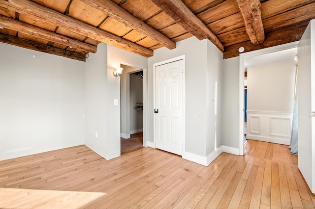 unfurnished room featuring beam ceiling, light hardwood / wood-style flooring, and wooden ceiling