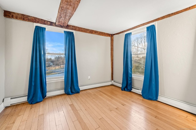 empty room featuring light wood-type flooring, baseboard heating, and a healthy amount of sunlight