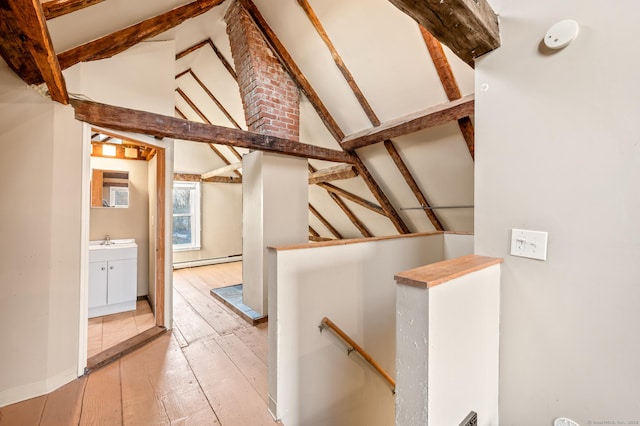 stairs with sink, beamed ceiling, high vaulted ceiling, a baseboard heating unit, and hardwood / wood-style flooring