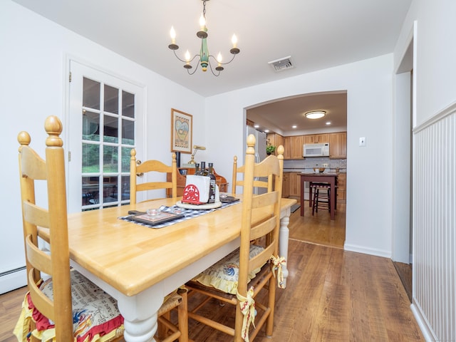 dining room featuring baseboard heating, a chandelier, and light hardwood / wood-style floors