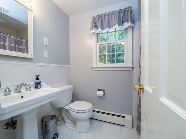 bathroom featuring a baseboard heating unit, toilet, tile walls, and tile patterned floors