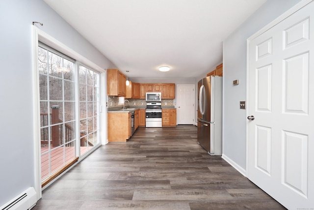 kitchen with sink, stainless steel appliances, baseboard heating, tasteful backsplash, and dark hardwood / wood-style flooring