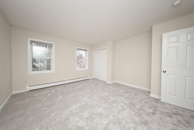 spare room featuring light carpet, a textured ceiling, and a baseboard heating unit