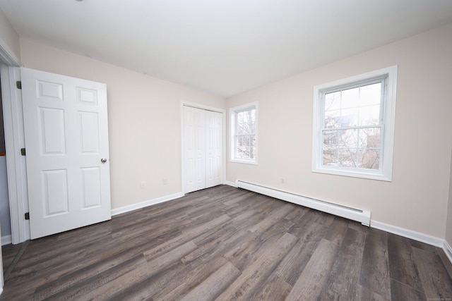 unfurnished bedroom with a closet, multiple windows, dark wood-type flooring, and a baseboard radiator