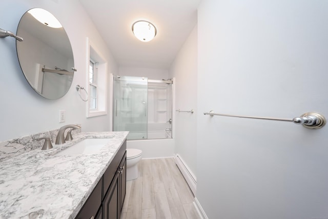 full bathroom featuring vanity, a baseboard heating unit, enclosed tub / shower combo, hardwood / wood-style floors, and toilet