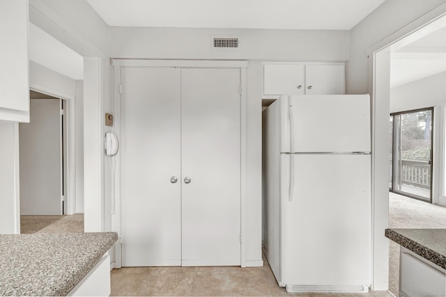 kitchen featuring white fridge and white cabinetry