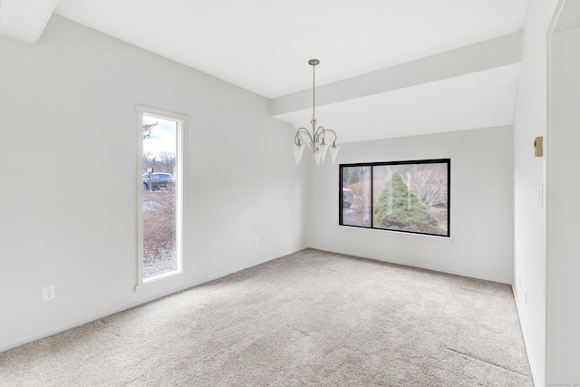 carpeted spare room with a chandelier