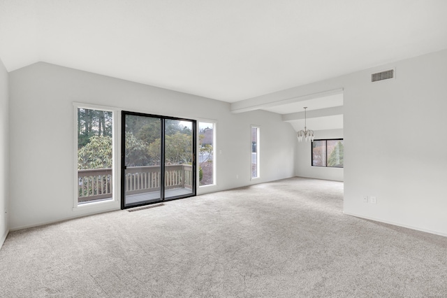 carpeted empty room with vaulted ceiling and a chandelier