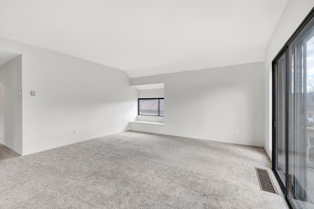 carpeted spare room with lofted ceiling