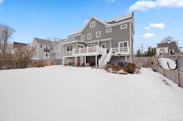 snow covered house with a wooden deck and solar panels