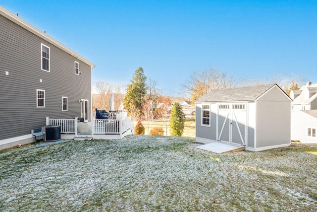 rear view of property featuring a shed, central air condition unit, a deck, and a lawn