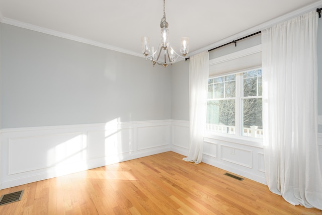 unfurnished room with ornamental molding, hardwood / wood-style flooring, and a notable chandelier