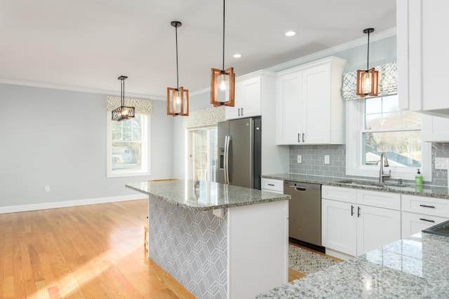 kitchen with sink, white cabinets, stainless steel appliances, and decorative light fixtures