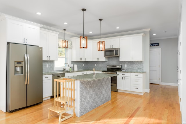 kitchen with a center island, white cabinets, stainless steel appliances, and decorative light fixtures