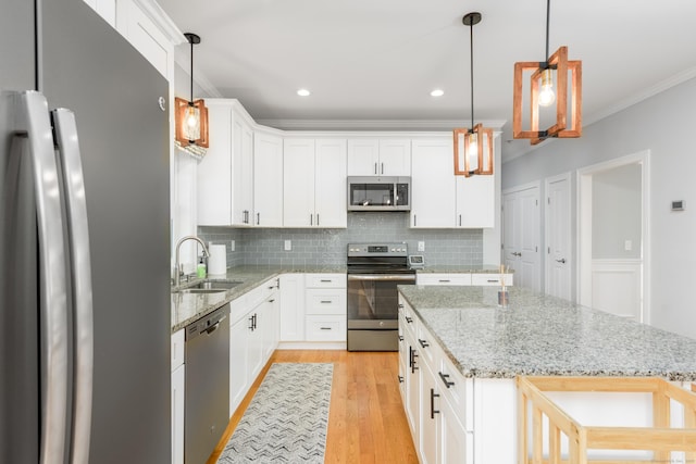 kitchen with sink, hanging light fixtures, a kitchen island, white cabinetry, and stainless steel appliances