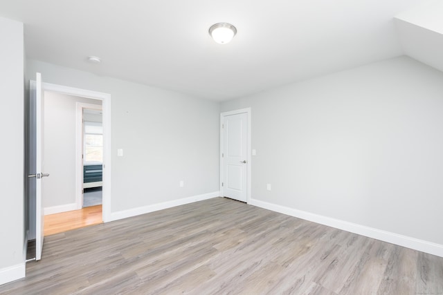 empty room with light wood-type flooring and vaulted ceiling