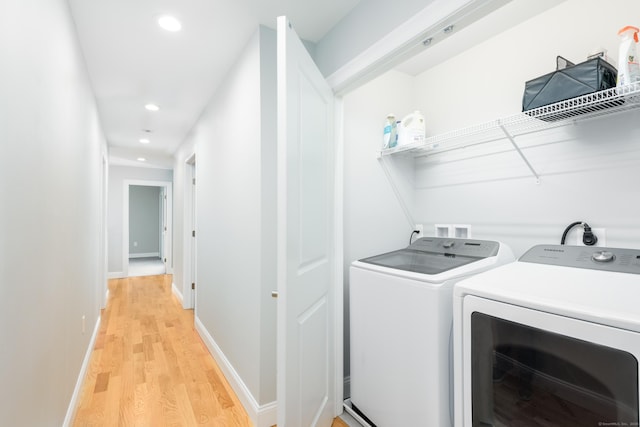 clothes washing area featuring washing machine and dryer and light hardwood / wood-style flooring