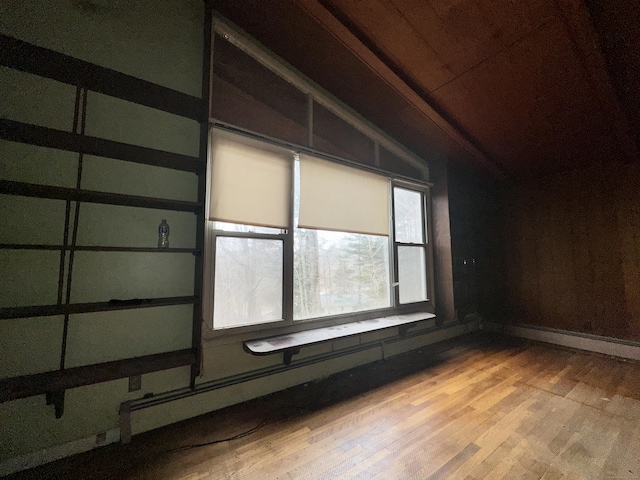 empty room featuring light hardwood / wood-style floors, wood ceiling, and lofted ceiling