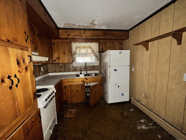 kitchen with sink, wooden walls, white appliances, and a baseboard heating unit