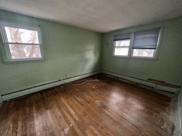 unfurnished room with baseboard heating, a textured ceiling, and dark hardwood / wood-style floors