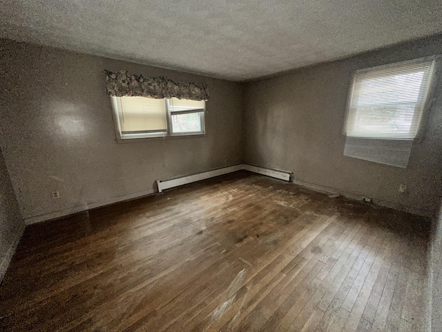 spare room with a textured ceiling, dark hardwood / wood-style flooring, and a baseboard heating unit