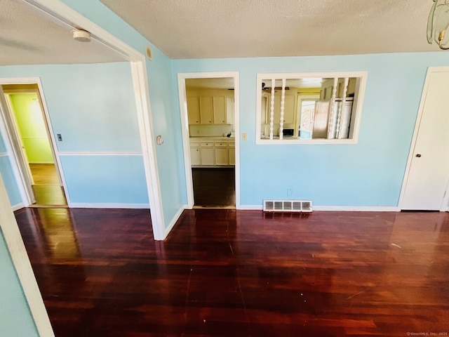 spare room with a textured ceiling and dark wood-type flooring