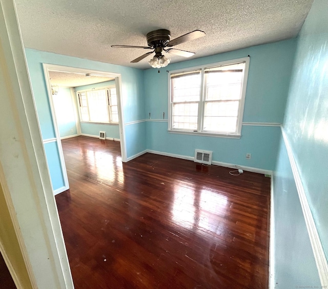 unfurnished room featuring dark hardwood / wood-style floors, ceiling fan, and a textured ceiling