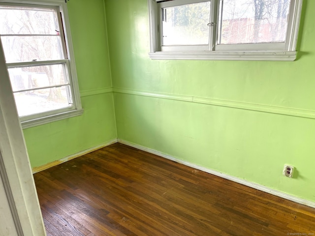 unfurnished room with plenty of natural light and dark wood-type flooring