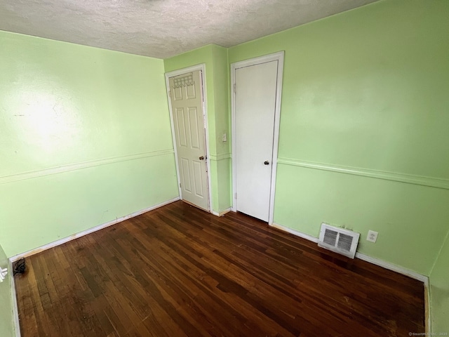 unfurnished room featuring a textured ceiling and dark hardwood / wood-style floors