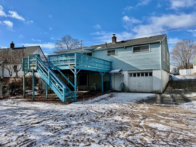 snow covered house with a garage and a wooden deck