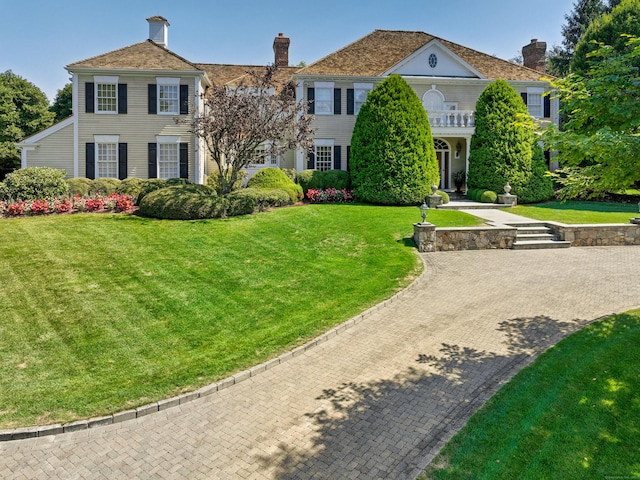 view of front of house with a balcony and a front yard