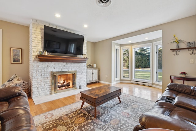 living room featuring a brick fireplace, a baseboard radiator, and light wood-type flooring