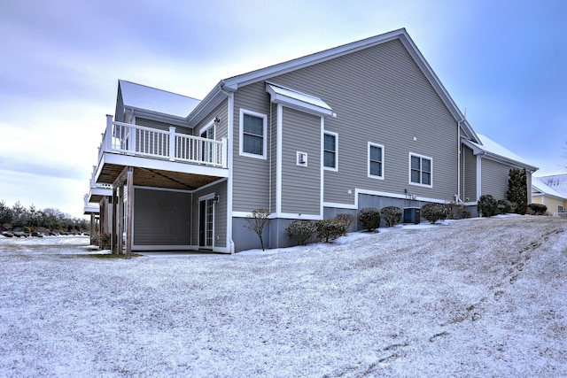 view of snowy exterior with central AC and a deck